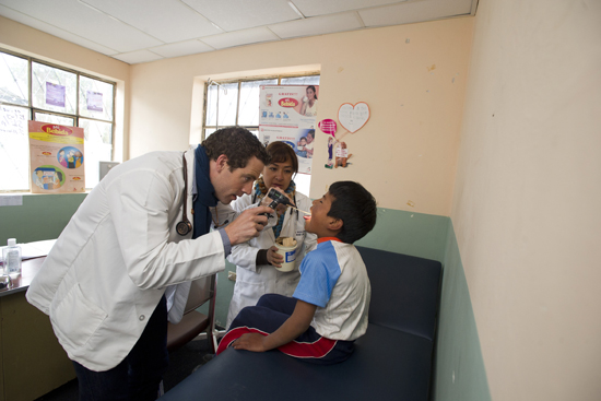 Kendall (left) and local doctor Patricia Reátegui (center) examine a boy in a rural Cacha clinic.
