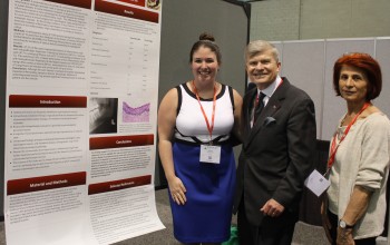 Megan Sullivan DMD 18 at her winning research poster with Dean Jeffrey W. Hutter and Assistant Director of Pre-doctoral Research Ms. Afaf Hourani.