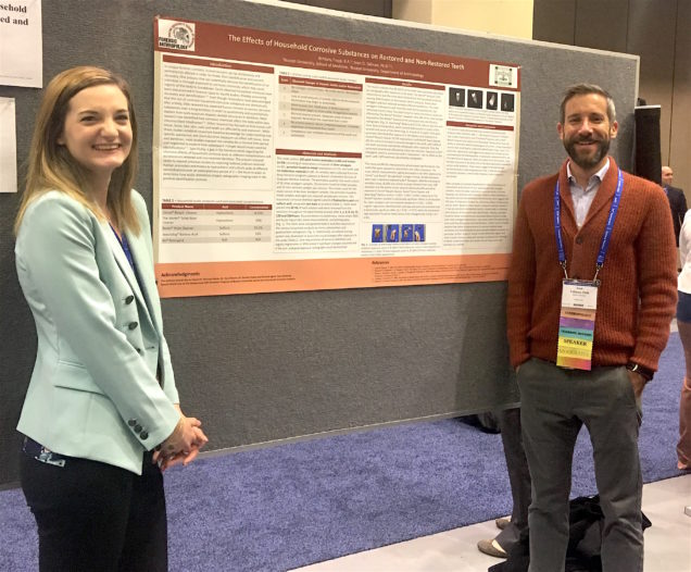 two students presenting research on a poster