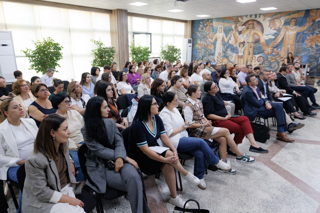 Approximately 70 people seated listening to a presentation