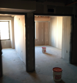 Dry wall in progress. View from living area into two-bedroom apartment. Dry wall in progress. View from living area into two-bedroom apartment.