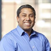 Head and shoulders shot of Dr. Norohana wearing light blue shirt smiling broadly.