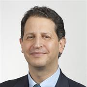 head and shoulders shot of Dan Alford wearing dark suit jacket and neck tie, light colored collared shirt, smiling gently