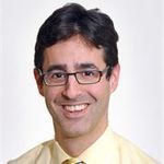 man with short black hair, dark framed eye glasses, smiling wearing yellow shirt and tie