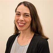 head and shoulders of woman with long straight dark hair wearing light shirt and dark suit jacket smiling broadly
