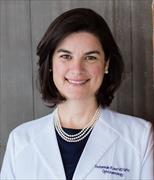 head and shoulders shot of Dr. Rowe wearing white coat with dark shirt and pearls, chin length dark hair, smiling