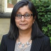 Head and shoulders of Dr. Sanchorawala wearing dark suit jacket, dark frame eyeglasses, slightly smiling