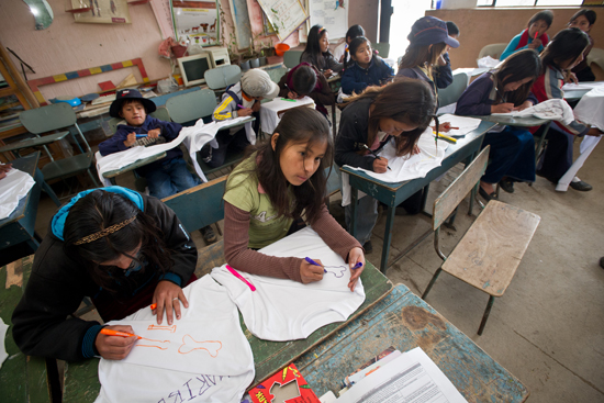 Cacha children draw arm bones on long-sleeved shirts during a health camp activity.