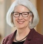 Woman with sliver chin length hair wearing dark framed eyeglasses smiling