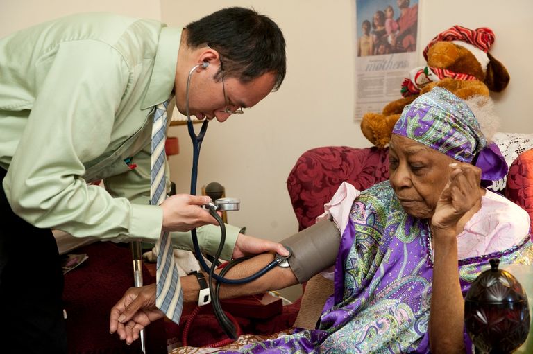 Healthcare professional measuring blood pressure of a person at home.