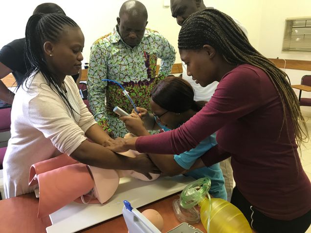 Medical training session in Zambia with participants practicing a procedure on a mannequin.