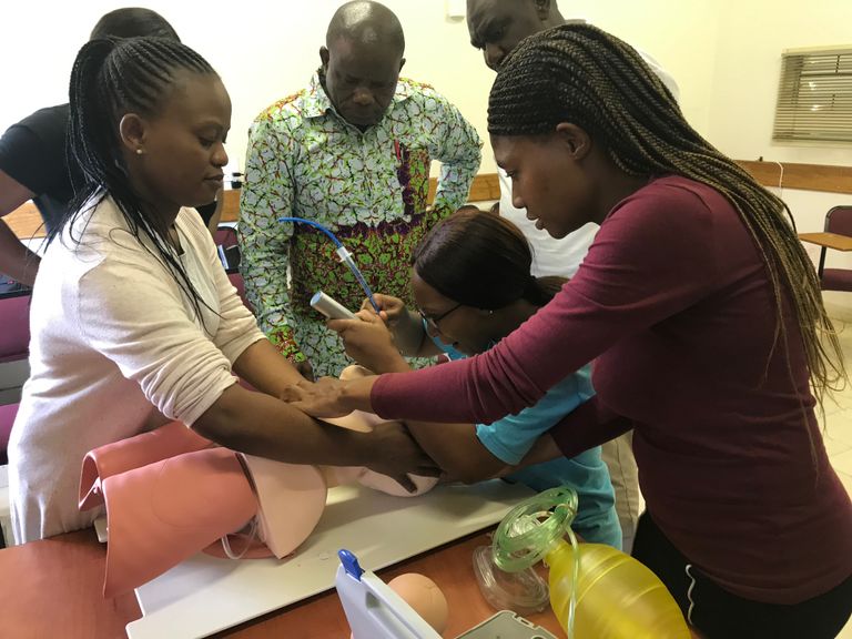 Medical training session in Zambia with participants practicing a procedure on a mannequin.