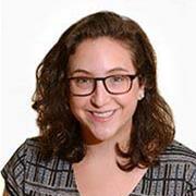 head and shoulders of woman with shoulder length brown hair and eyeglasses smiling