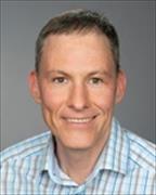 Head and shoulders shot of Markus.Bosmann wearing blue and white plaid open collar button down shirt, smiling 