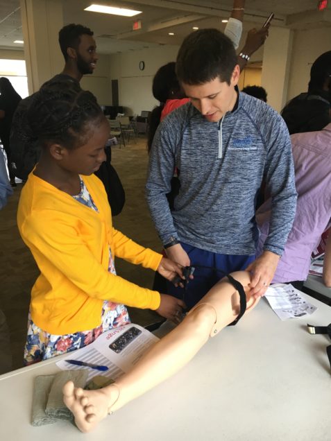 BU alum and current BMC resident Captain Yevgeniy Maksimenko, MD teaches military tourniquet skills to a student from the Boston Area Health Education Center.