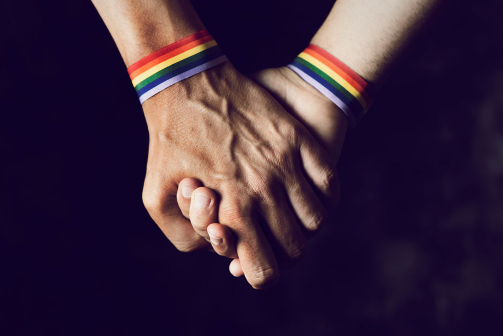 Two hands with rainbow bracelets