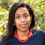 Dr. Pierre in navy top, red necklace, smiling