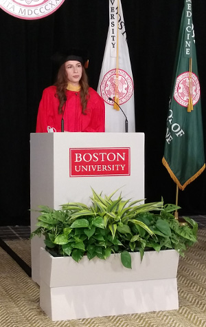 Sara Sakowitz in red robe behind white podium giving her speech