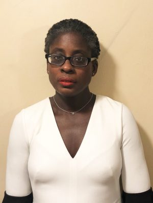 Photo of Ridiane Denis wearing white blouse and black eye glasses.