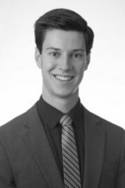 Headshot in black and white of Preston Butler in a suit and tie.