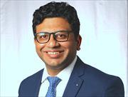 head and shoulders image of Ashish Verma wearing a blue suit and blue tie., eyeglasses, smiling broadly