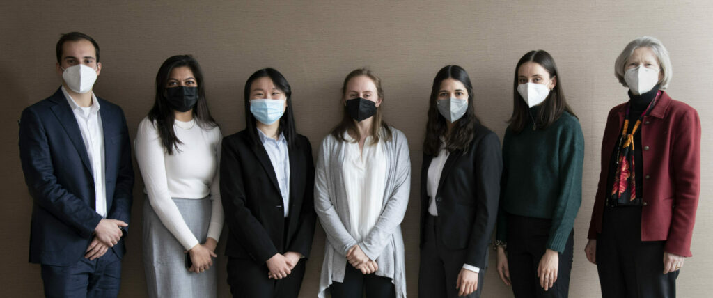 Poster presenters with masks lined up against a wall