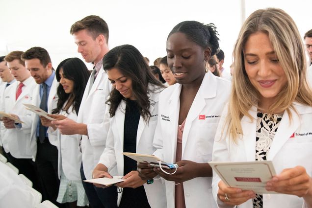 Students reciting Hippocratic Oath under tent