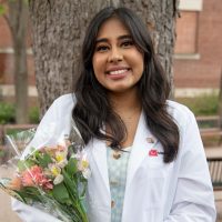 Sara Shoushtari outside on Talbot Green wearing her whitecoat holding flowers after the ceremony.