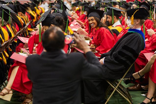 A proud parent takes a photo of their graduating daughter