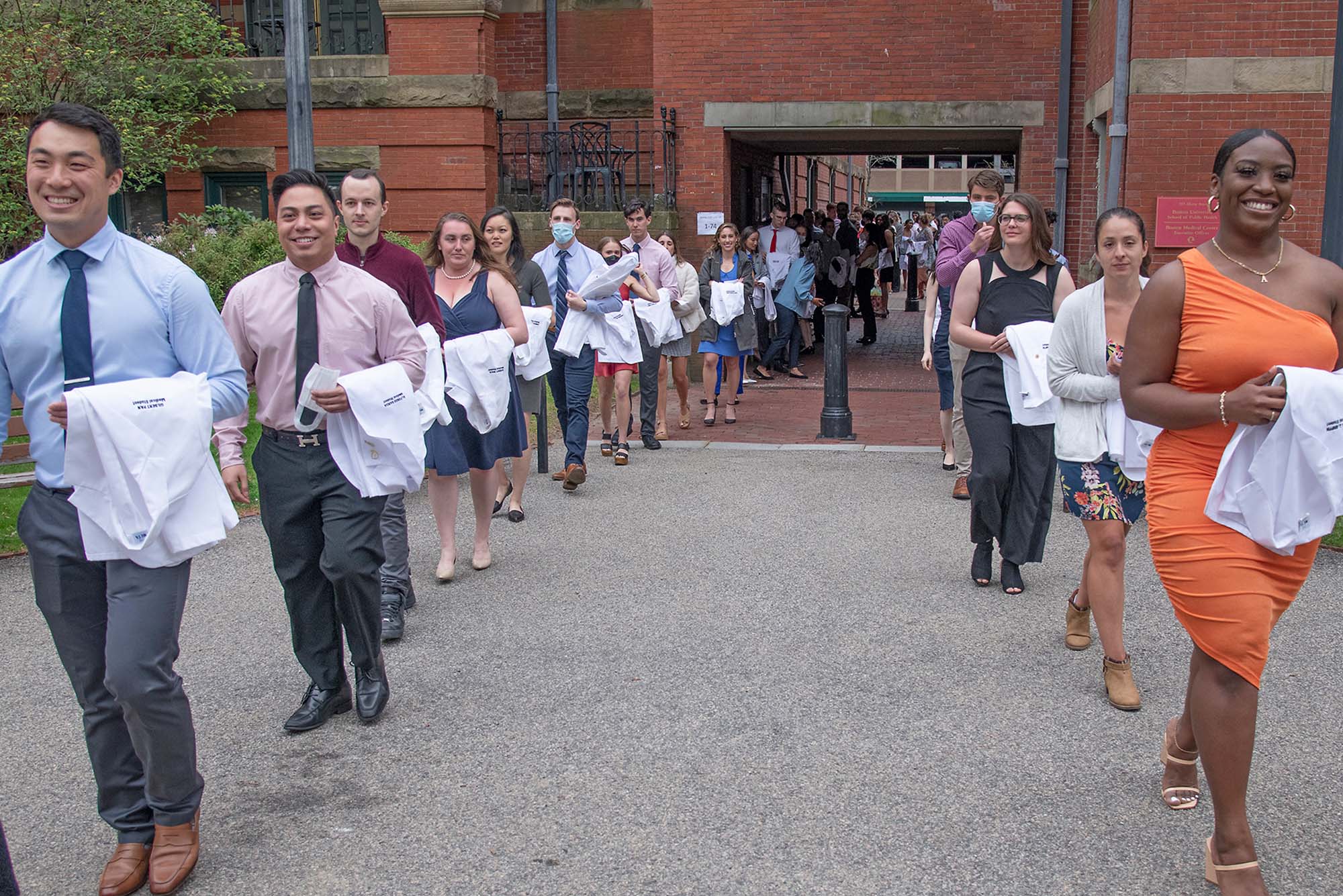 Students lining up on Talbot Green with whitecoats over their arms before ceremony