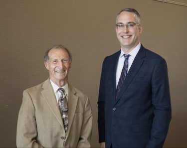 Dr. Salant in beige suit standing next to Dr. Beck in dark blue suit