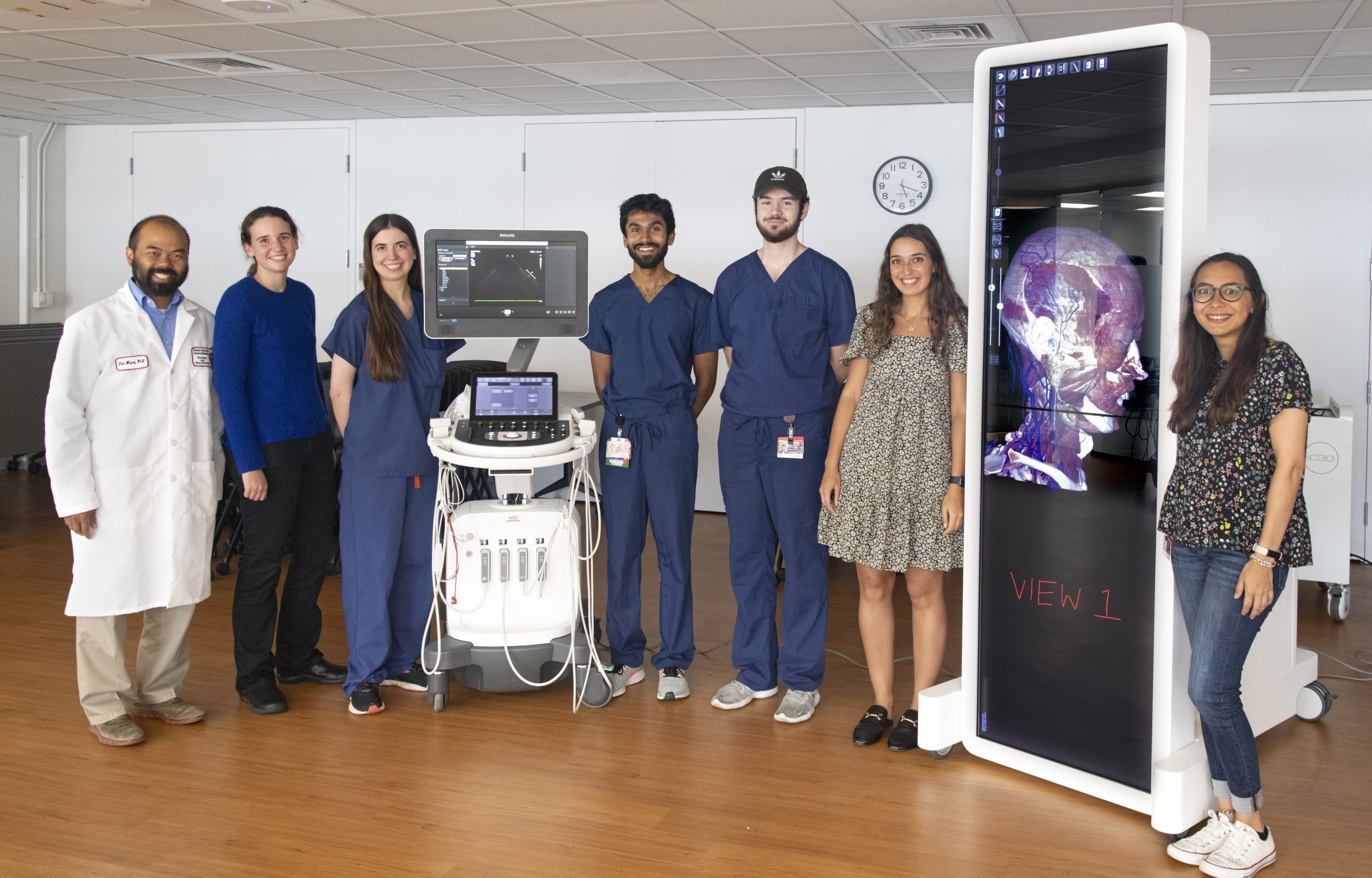Seven faculty, staff and students stand next to the Anatomage and ultrasound machines.