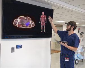 Student stands in front of large monitor mounted on a wall that show demo of VH Dissector