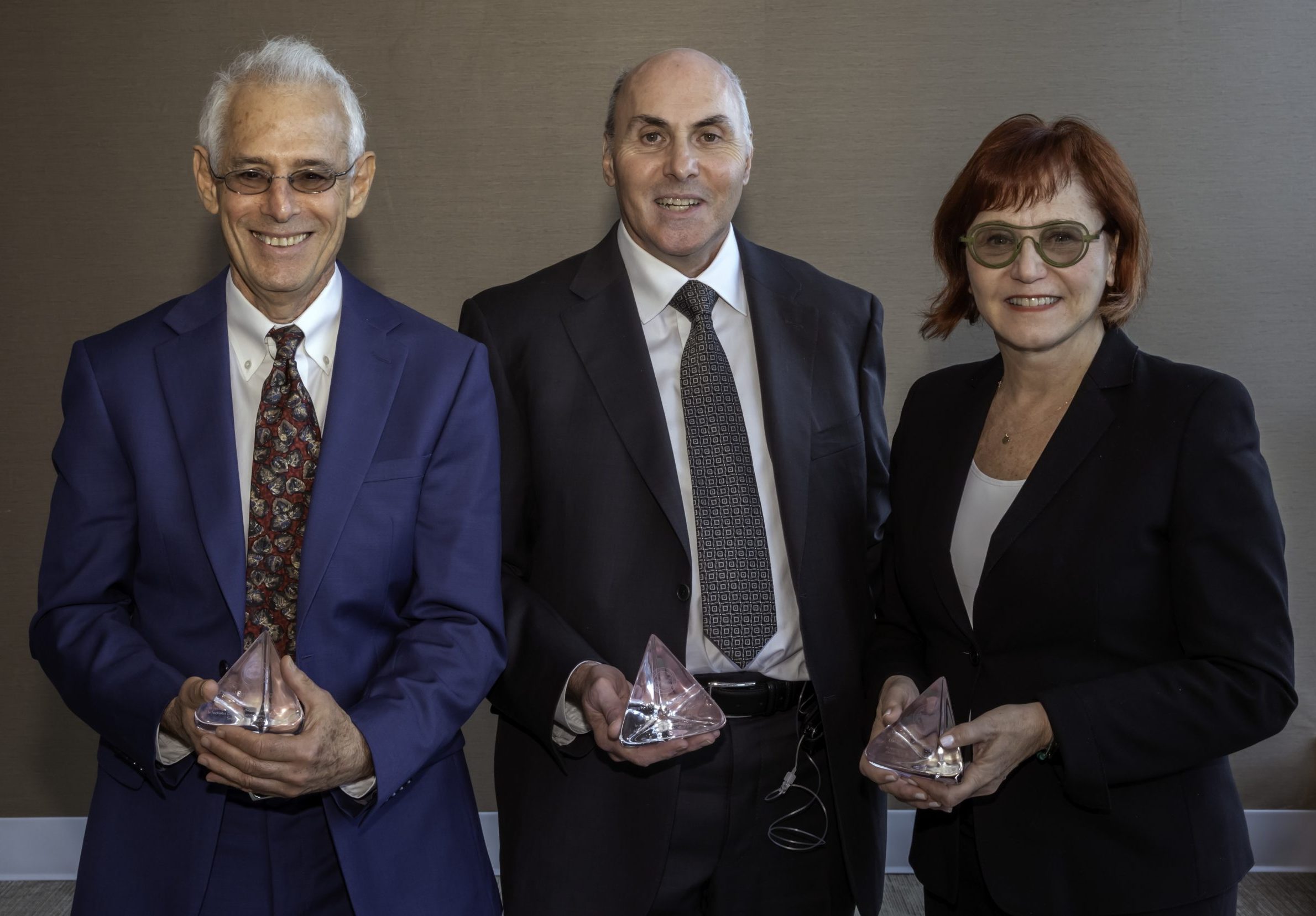 Three awardees standing holding crystal blocks