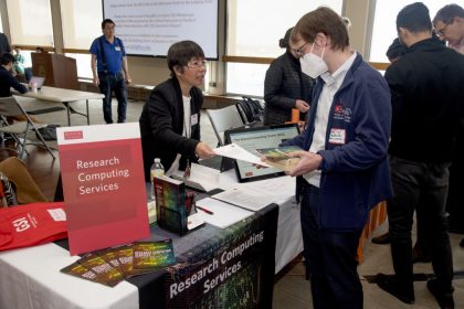 wo people talking at a table with a research computing services sign.