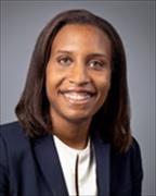 Head and shoulders shot of Samantha Rawlins Pilgrim wearing white shirt, navy suit jacket, straight brown hair smiling broadly