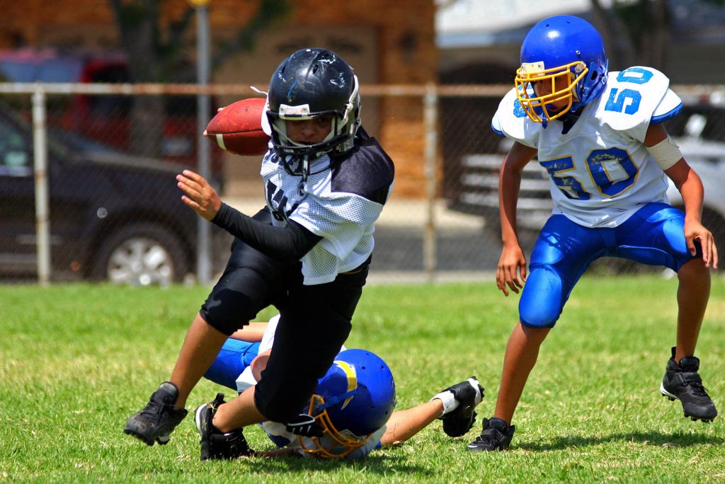 Young american football player running back breaking away from an attempted tackle. All logos and trademarks from uniforms, helmets and cleats have been removed in Photoshopuniform running on grass