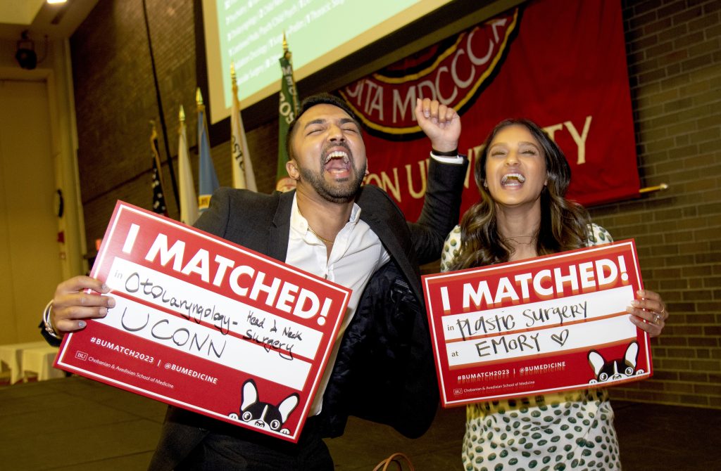 two students smiling and celebrating match day holding I matched signs arms raised