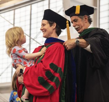 PhD candidate being hooded, holding child