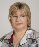 Head and shoulders shot of Erita Ikonomi wearing a gray and white suit jacket, blond hair and light colored eyeglasses