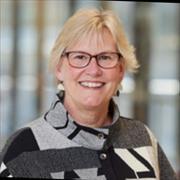 Head and shoulders of woman with blond hair and eyeglasses smiling broadly