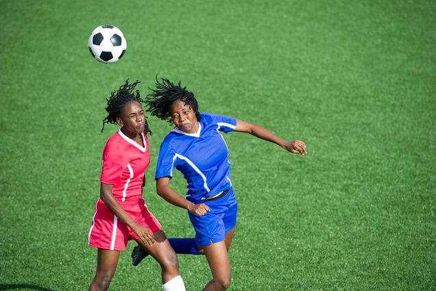 Two female soccer players competing for the ball, aerial view.