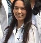 Woman with straight, long dark hair, wearing lab coat, smiling broadly into camera