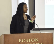 Woman with long dark hair standing behind a podium