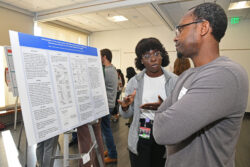 A man and a woman discussing a poster on an easel.