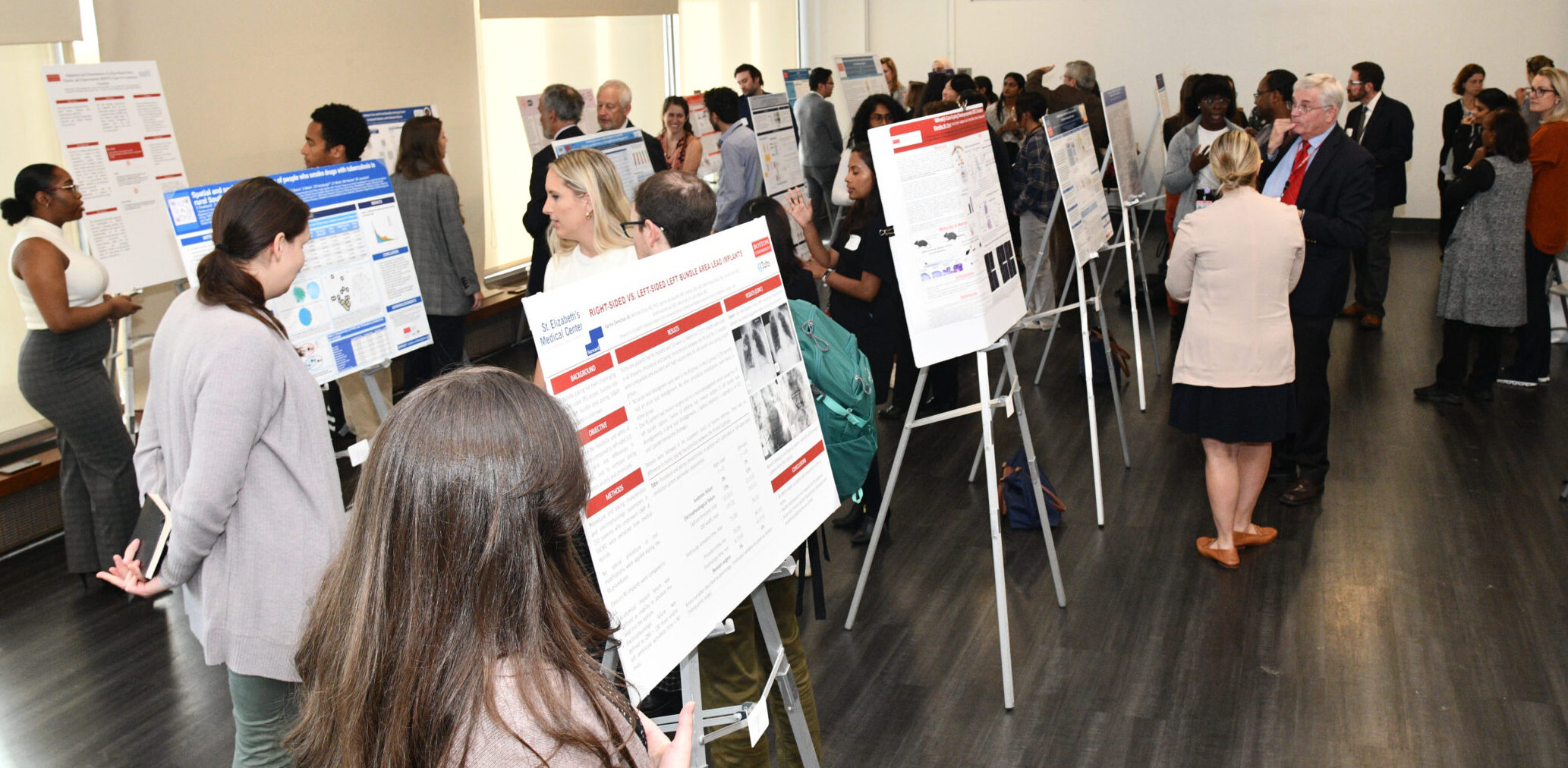 Many large posters on easels surrounded by people looking at posters