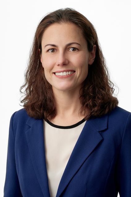 woman with shoulder length brown wavy hair wearing blue suit jacket smiling