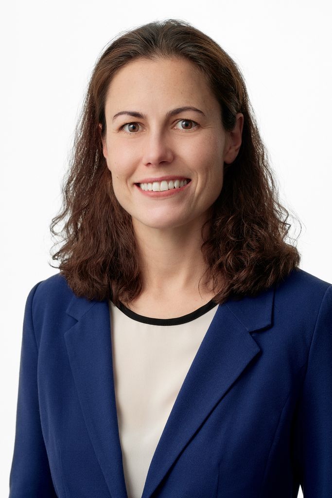 woman with shoulder length brown wavy hair wearing blue suit jacket smiling