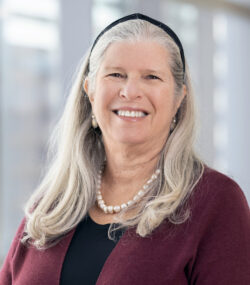woman with below shoulder length gray/blond hair smiling broadly