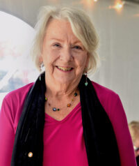 Woman wearing bright pink shirt standing under white outdoor tent